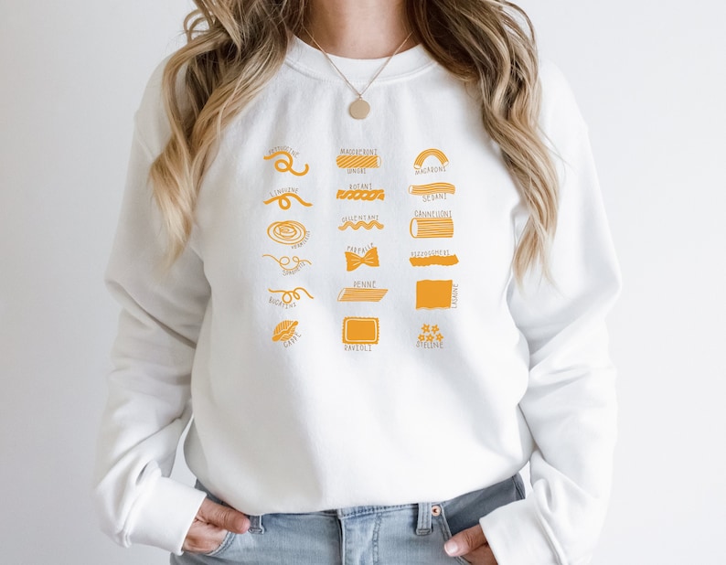 Peut inclure: Sweat-shirt blanc avec un graphique de diff&eacute;rents types de p&acirc;tes avec leurs noms imprim&eacute;s sous chaque illustration. Les formes de p&acirc;tes sont soulign&eacute;es en orange.