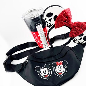 May include: A black fanny pack with Mickey and Minnie Mouse graphics, a red and white polka dot tumbler, and a headband with skull ears and a red sequin bow. The items are Disney-themed.