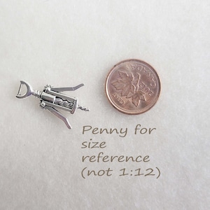 May include: A silver-toned, miniature corkscrew with a lever, a worm, and a handle. The corkscrew is next to a Canadian penny for size reference. The text "Penny for size reference (not 1:12)" is below the penny.
