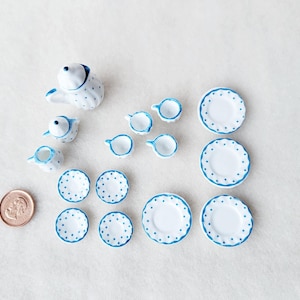 May include: A miniature tea set with blue and white polka dot designs. The set includes a teapot, creamer, sugar bowl, four cups, and six saucers.
