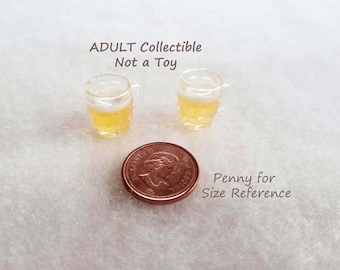 May include: Two miniature clear glass beer mugs filled with a yellow liquid and white foam, positioned above a copper-colored penny for size reference. The text ADULT Collectible Not a Toy and Penny for Size Reference is visible in the image.