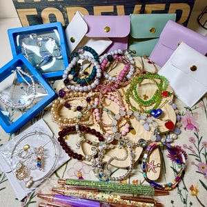 May include: A white ceramic mug with a black handle and the text "But First, Coffee" in a bold, black font. The mug is set against a blurred background, suggesting a cozy setting.