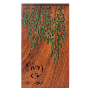 May include: Wooden pet memorial plaque with a green leafy design and the inscription "Chewy 2010 - 2024" with a paw print heart.