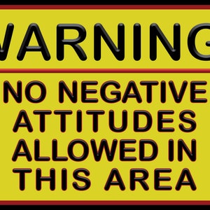 May include: Yellow warning sign with black text that reads "WARNING! NO NEGATIVE ATTITUDES ALLOWED IN THIS AREA."