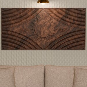 May include: A rectangular dark brown wooden wall art panel featuring a carved sun motif in the center. The wood grain is visible throughout the piece, which is accented by symmetrical, curved, wave-like patterns radiating from the central sun design.