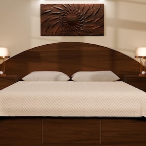 May include: A dark wood bed frame featuring a large, arched headboard and two matching nightstands. The bed is dressed in a white coverlet with a subtle chevron pattern. Two lamps with white shades sit on the nightstands, flanking the bed.