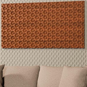 May include: A rectangular wall panel with a repeating terracotta-colored hexagonal pattern mounted on a textured off-white wall. The panel is flanked by vertical wood slat panels and positioned above a beige sofa with matching throw pillows.