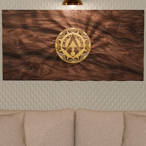 Peut inclure: Une pièce d'art mural rectangulaire en bois brun foncé avec un emblème circulaire doré proéminent au centre. L'emblème présente un motif géométrique en rayons de soleil avec un motif triangulaire central. Le grain du bois est visible.