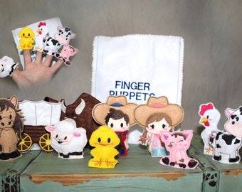 May include: A collection of felt finger puppets featuring farm animals, cowboys, and a covered wagon. The puppets include a horse, sheep, chick, cow, and pig. A white cloth with "FINGER PUPPETS" printed on it is in the background.