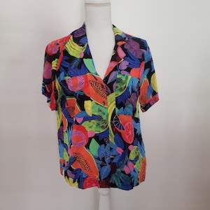 May include: A short-sleeved button-up shirt with a colorful tropical fruit print. The shirt is made of a lightweight fabric and has a relaxed fit.