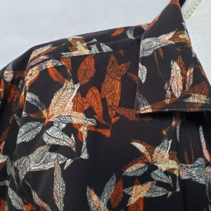 May include: Black button-down shirt with a brown and white leaf print.