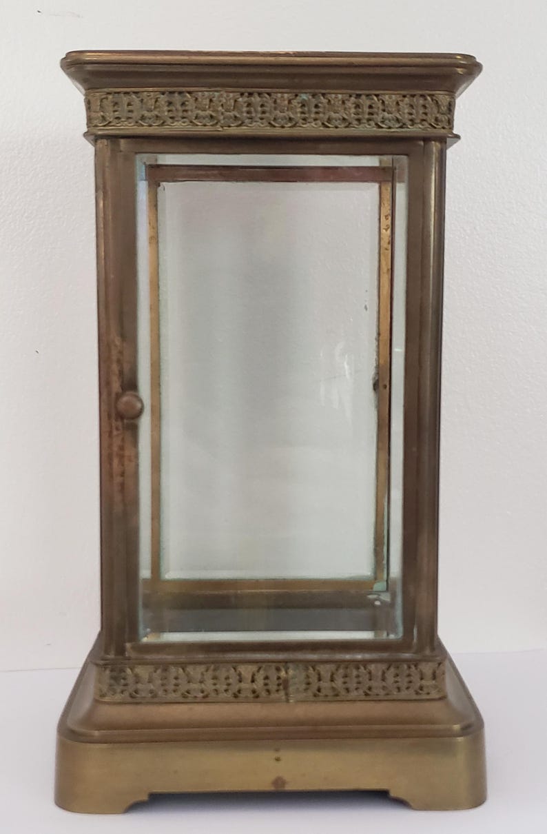 K&ouml;nnte beinhalten: Eine Vitrine aus Messing mit einer Glasfront und einer Glast&uuml;r. Die Vitrine hat ein dekoratives Design an der Ober- und Unterseite.