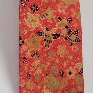 May include: A red silk tie with a floral pattern in shades of gold and black.