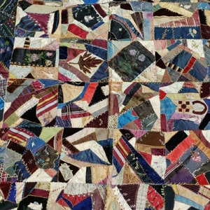 May include: A patchwork quilt made from a variety of fabrics in shades of blue, red, brown, and white. The quilt is made up of many small squares and rectangles, each with a different pattern. The quilt is a beautiful example of traditional quilting.