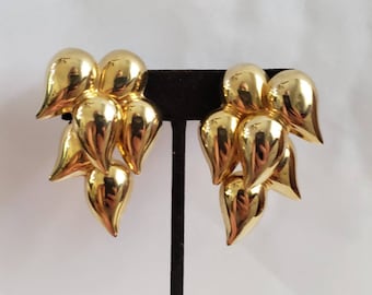 May include: A pair of gold tone dangle earrings with a cluster of teardrop shaped charms.