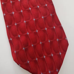 May include: A red silk tie with a geometric pattern of white and blue diamonds.