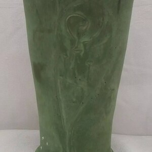 May include: A green ceramic vase with a swirling design. The vase has a wide mouth and a narrow base.