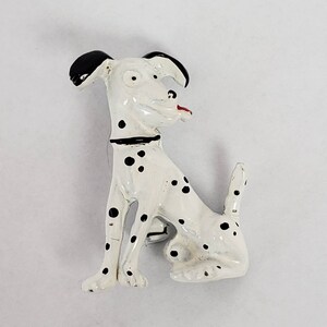 Könnte beinhalten: Eine weiße und schwarze Dalmatiner-Hundefigur mit roten Akzenten. Die Figur ist aus Metall und hat eine glänzende Oberfläche.
