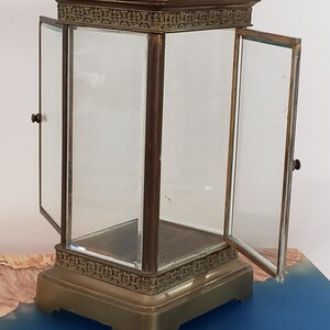 K&ouml;nnte beinhalten: Eine Vitrine aus Messing mit Glast&uuml;ren und einem Glasboden. Die Vitrine hat einen dekorativen Rand um die Ober- und Unterseite. Die T&uuml;ren sind offen und die Vitrine ist leer.
