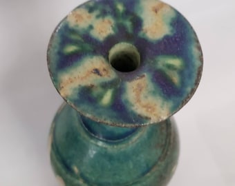 May include: A small, green and blue ceramic vase with a wide, flared opening. The vase has a mottled glaze with shades of green, blue, and yellow.