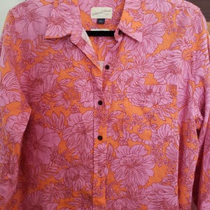 May include: A long-sleeved button-down shirt with a floral print. The shirt is orange with pink flowers. The brand name "Universal Thread" is visible on the label.
