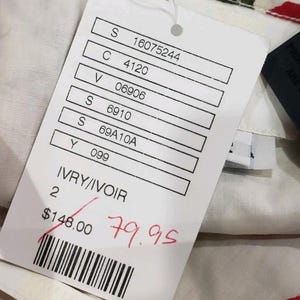 May include: A white tag with printed details and a barcode. The tag reads "IVRY/IVOIR" and has a crossed-out price of $148.00 with a handwritten price of $79.95. The tag is attached to a garment with a floral pattern.