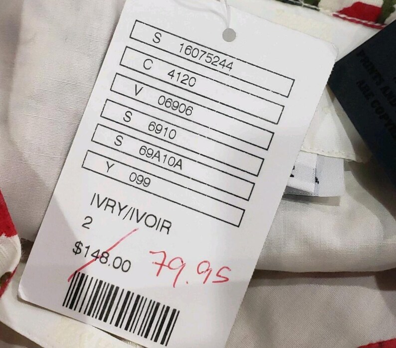 May include: A white tag with printed details and a barcode. The tag reads "IVRY/IVOIR" and has a crossed-out price of $148.00 with a handwritten price of $79.95. The tag is attached to a garment with a floral pattern.