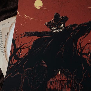 May include: A rectangular art print featuring a dark, shadowy scarecrow figure with a glowing, jagged-toothed pumpkin head. The scene is set against a deep red background with a full moon, bare trees, and a small barn structure at the bottom.