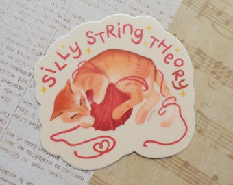 May include: A sticker with a cartoon cat playing with a ball of yarn. The sticker has the text "Silly String Theory" with stars around the text.