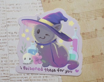 May include: A die-cut sticker featuring a grey cat wearing a purple witch hat, surrounded by potion bottles, a small skull, and a pink flower. The text "i Poisoned these for you" is printed at the bottom in a dark purple, rounded font.
