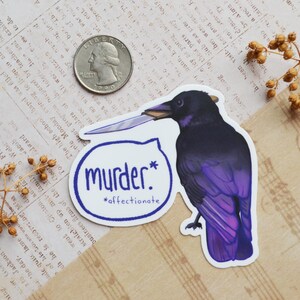 May include: A sticker featuring a purple and black crow holding a knife. The sticker has the text "murder*" with the word "affectionate" underneath.