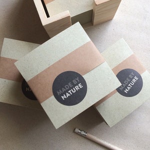 Könnte beinhalten: Stapel brauner und grüner Notizblöcke mit einem braunen Papierband und einem schwarzen runden Aufkleber mit der Aufschrift "Made by Nature".