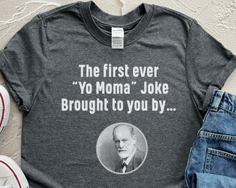 May include: A dark gray t-shirt with the text "The first ever "Yo Momma" Joke Brought to you by..." and a black and white image of Sigmund Freud.