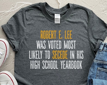 May include: A dark gray t-shirt with white text that reads "ROBERT E. LEE WAS VOTED MOST LIKELY TO SECEDE IN HIS HIGH SCHOOL YEARBOOK".