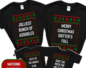 May include: Black t-shirts with humorous Christmas-themed text and festive patterns. The shirts feature phrases like "Jolliest Bunch of Assholes," "Merry Christmas Shitter's Full," "Jelly of the Month Club," and "Save the Neck for Me Clark."