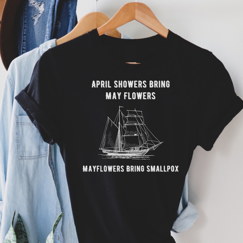 K&ouml;nnte beinhalten: Schwarzes T-Shirt mit wei&szlig;em Text, der "April showers bring May flowers" und "Mayflowers bring smallpox" lautet. Zwischen den beiden Textzeilen befindet sich eine Zeichnung eines Schiffes.