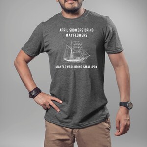 K&ouml;nnte beinhalten: Ein dunkel-helles graues T-Shirt mit einer wei&szlig;en Grafik eines Schiffes und dem Text "April showers bring May flowers. Mayflowers bring smallpox."
