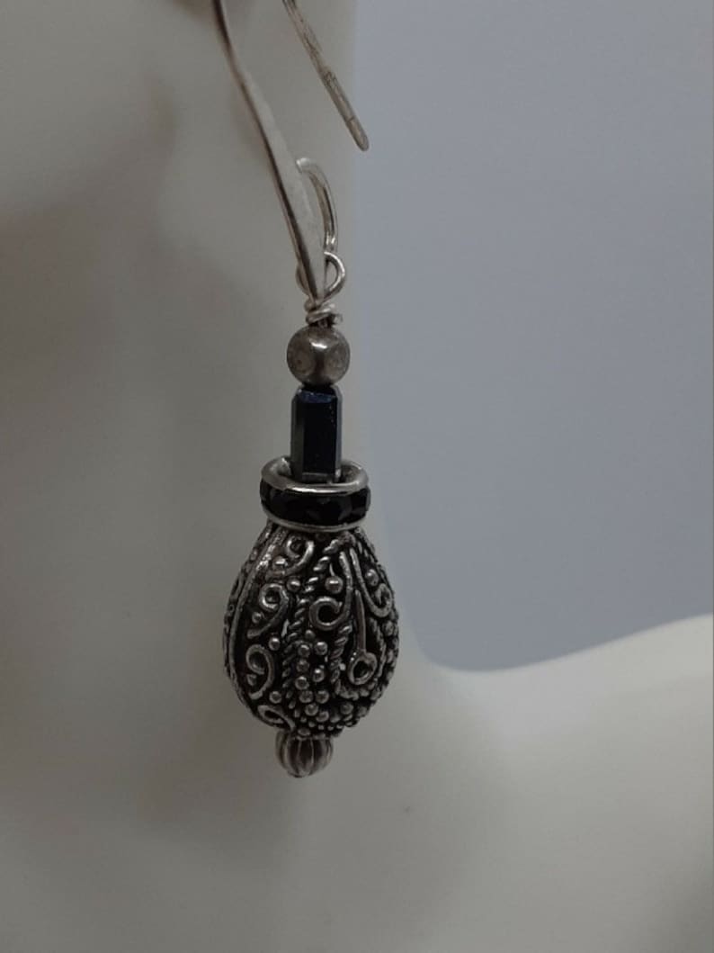 Silver tone ornate drop bead with dark blue crystal accents