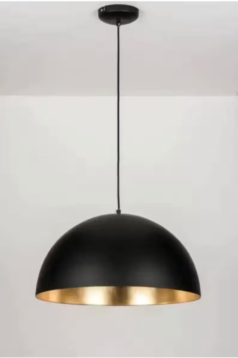 May include: A black pendant light with a gold interior. The light fixture has a dome-shaped shade.