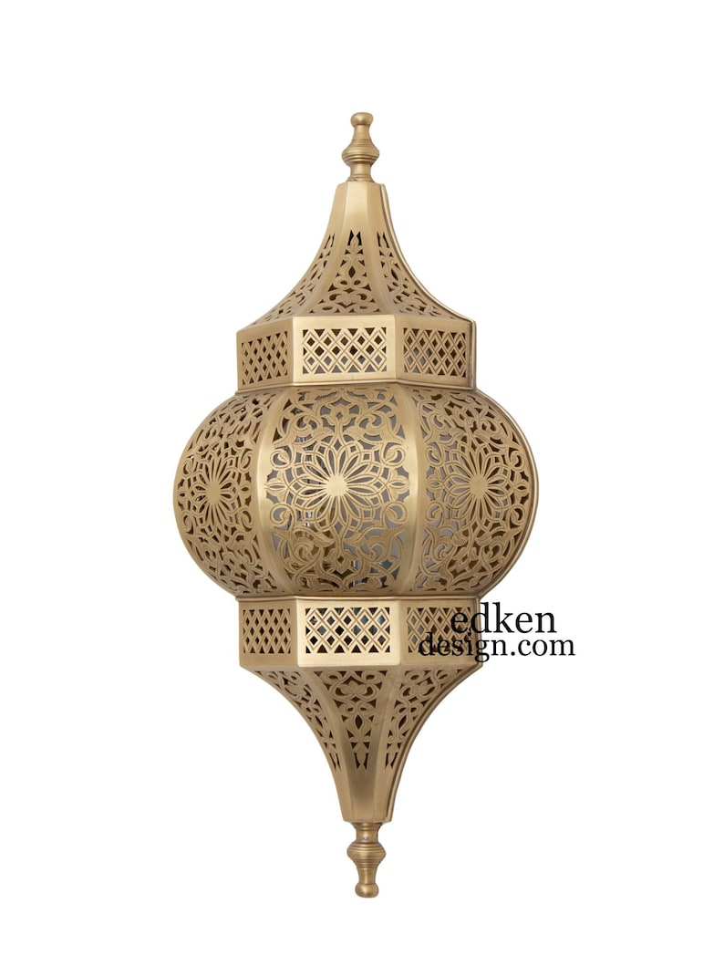 May include: A gold metal wall sconce with intricate cut-out designs. The sconce has a round, bulbous shape with a pointed top and bottom.