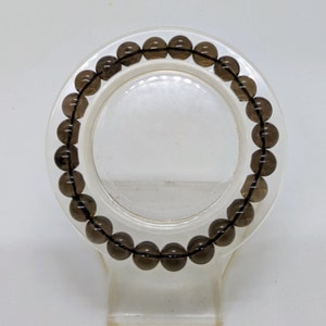 May include: A dark brown gemstone bracelet with round beads.