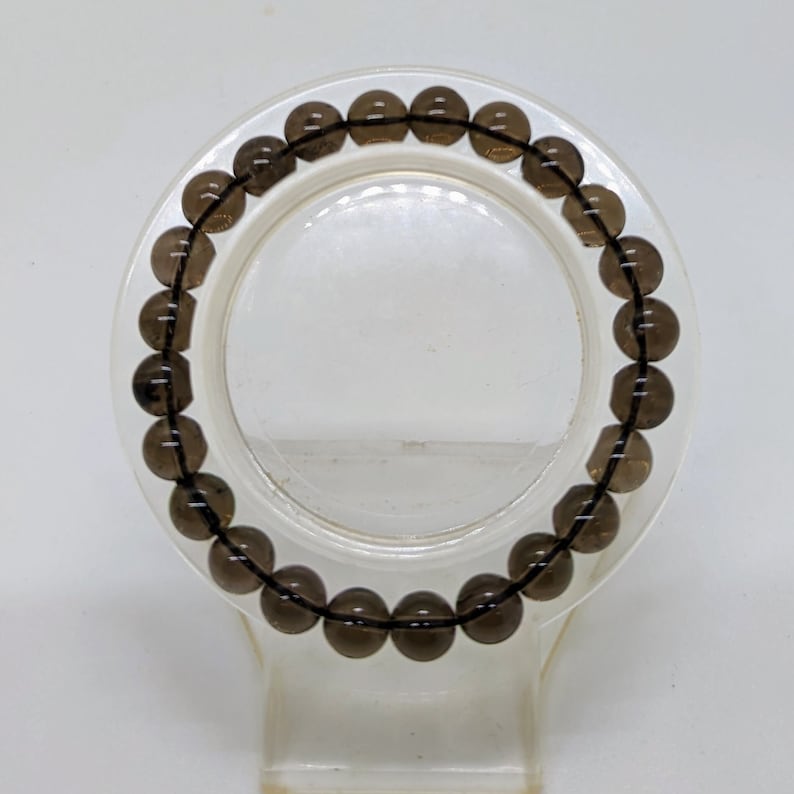 May include: A dark brown gemstone bracelet with round beads.