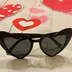 May include: Black heart-shaped sunglasses with dark lenses.