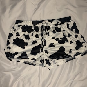 May include: White and black cow print shorts with a drawstring waist.