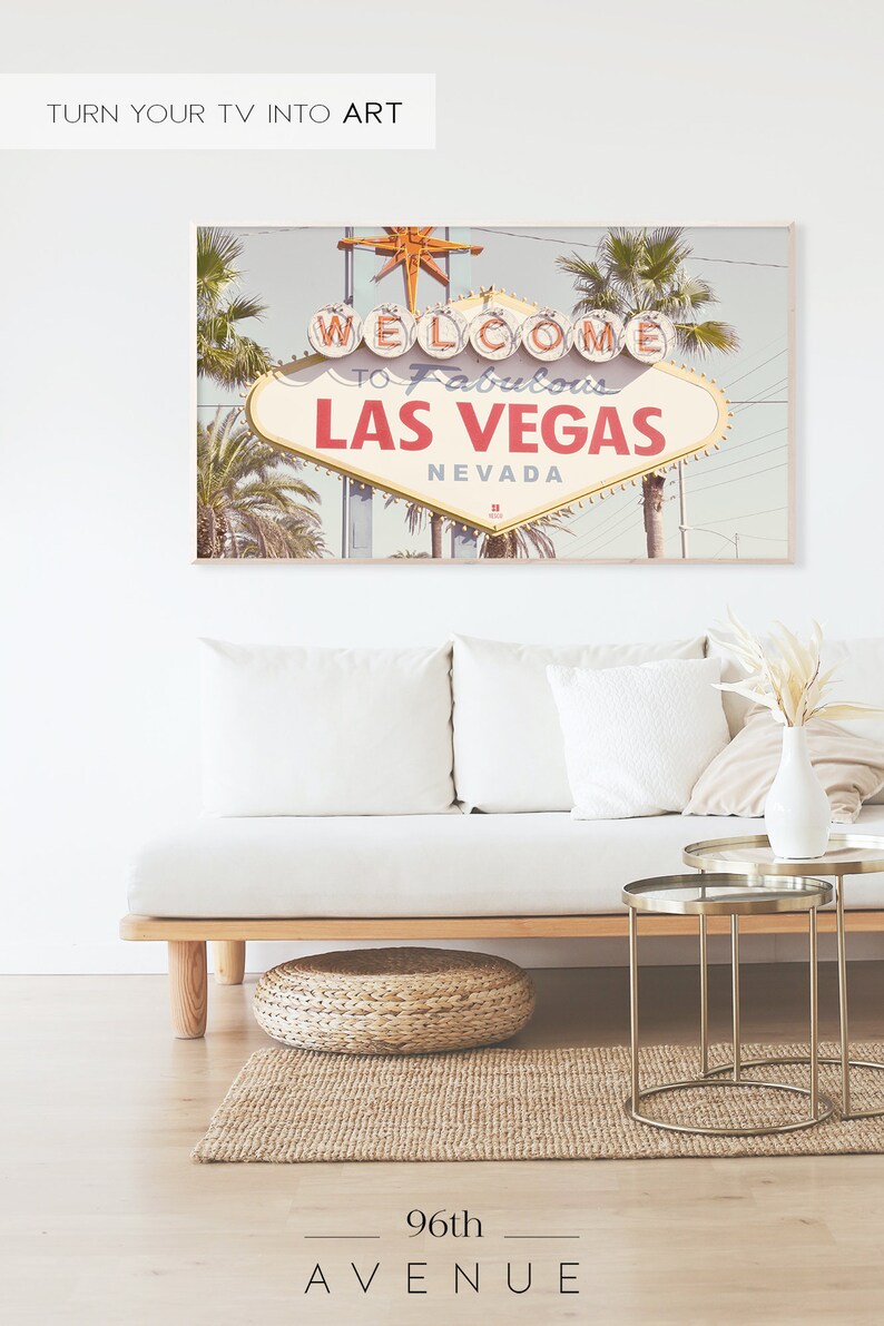 May include: A vintage-style photograph of the iconic "Welcome to Fabulous Las Vegas" sign with palm trees in the background. The sign is lit up with neon lights and the sky is a light blue. The image is perfect for a retro-themed home decor.