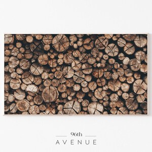 May include: A close-up image of a wall of stacked wood logs, showing the cross-section of the logs. The logs are various shades of brown and have a natural, rustic look.
