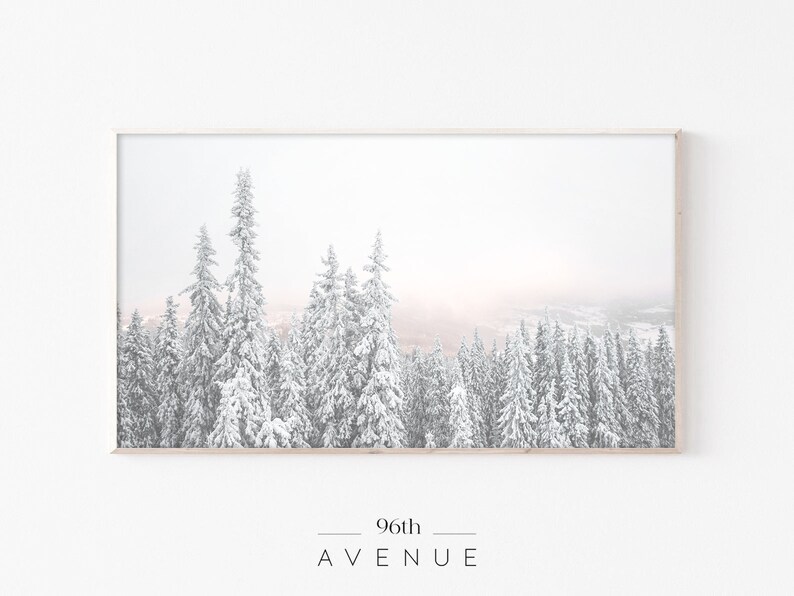 May include: A framed photograph of a snowy forest scene with tall evergreen trees covered in white snow. The background is a soft, hazy pink and white.