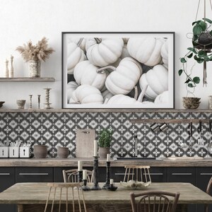 Puede incluir: Una fotograf&iacute;a enmarcada de una colecci&oacute;n de calabazas blancas. La fotograf&iacute;a est&aacute; colgada en una pared sobre una encimera de cocina con un salpicadero de azulejos con un patr&oacute;n blanco y negro.