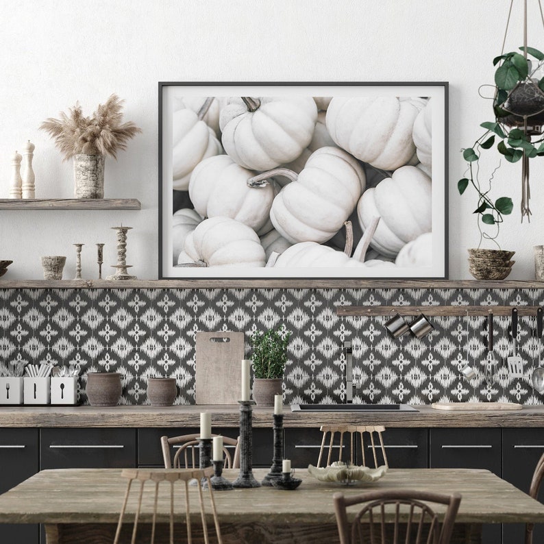 Puede incluir: Una fotograf&iacute;a enmarcada de una colecci&oacute;n de calabazas blancas. La fotograf&iacute;a est&aacute; colgada en una pared sobre una encimera de cocina con un salpicadero de azulejos con un patr&oacute;n blanco y negro.