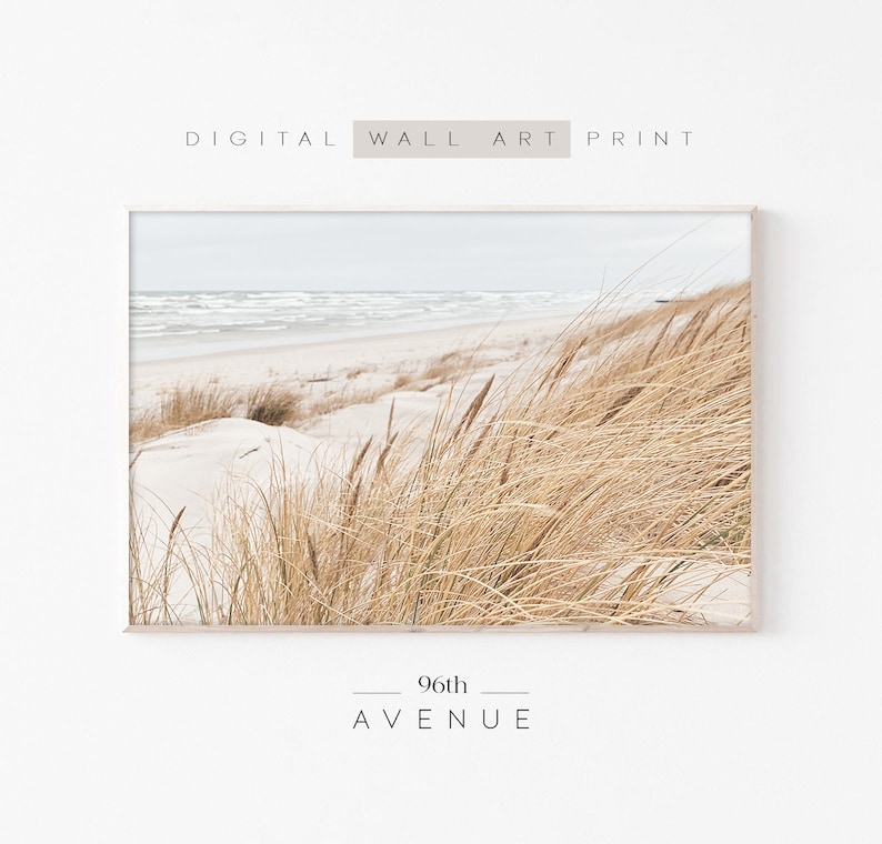May include: A digital print of a beach scene with tall, golden grass blowing in the wind. The beach is white sand and the ocean is blue with white waves. The print is framed in a light wood frame. The text "96th AVENUE" is printed below the image.